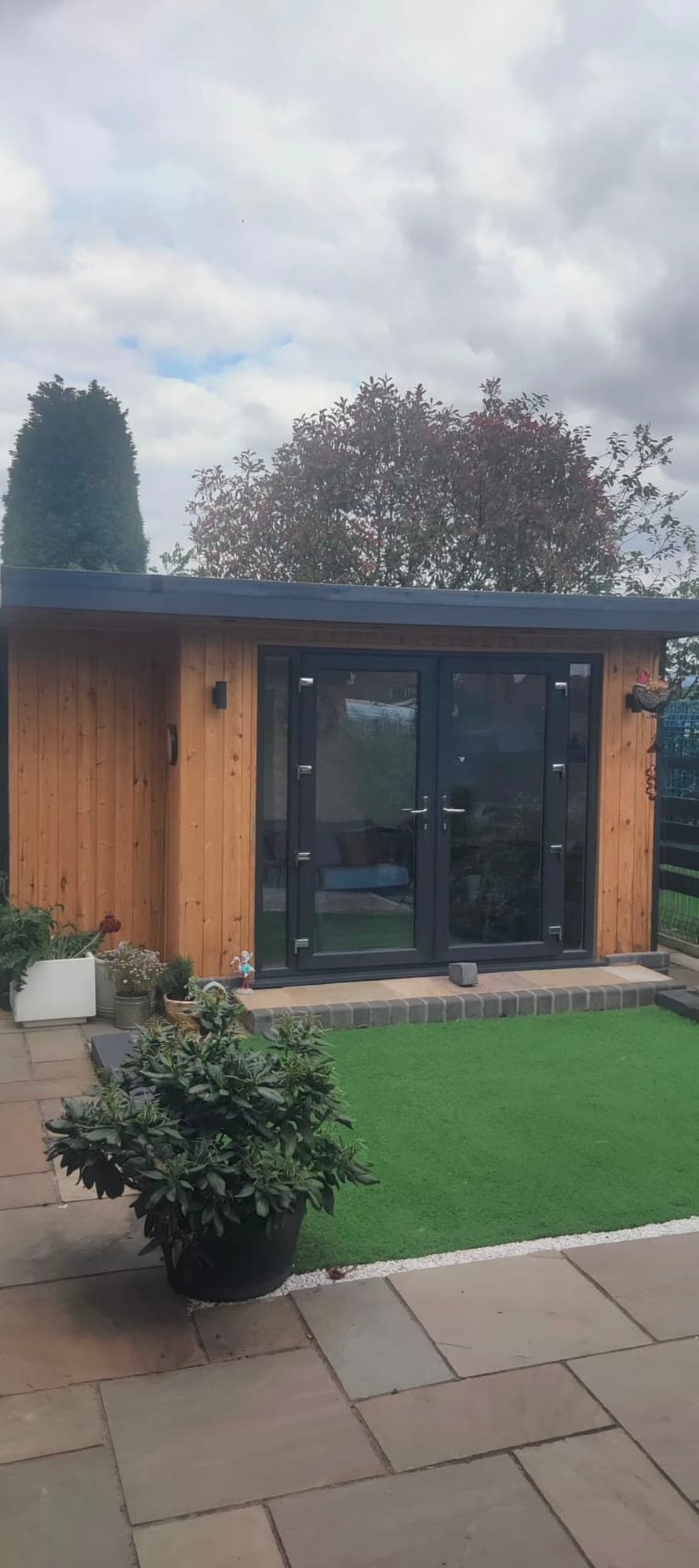 Cedar-clad garden room with anthracite French doors, opening onto an Indian sandstone patio and lawn